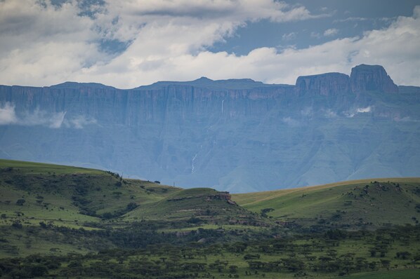 Un paisaje montañoso con un risco imponente y una cascada.