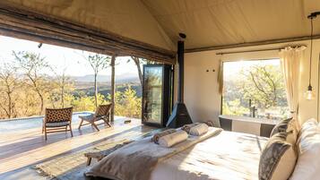 Un dormitorio con una cama grande, vistas al exterior y una chimenea.