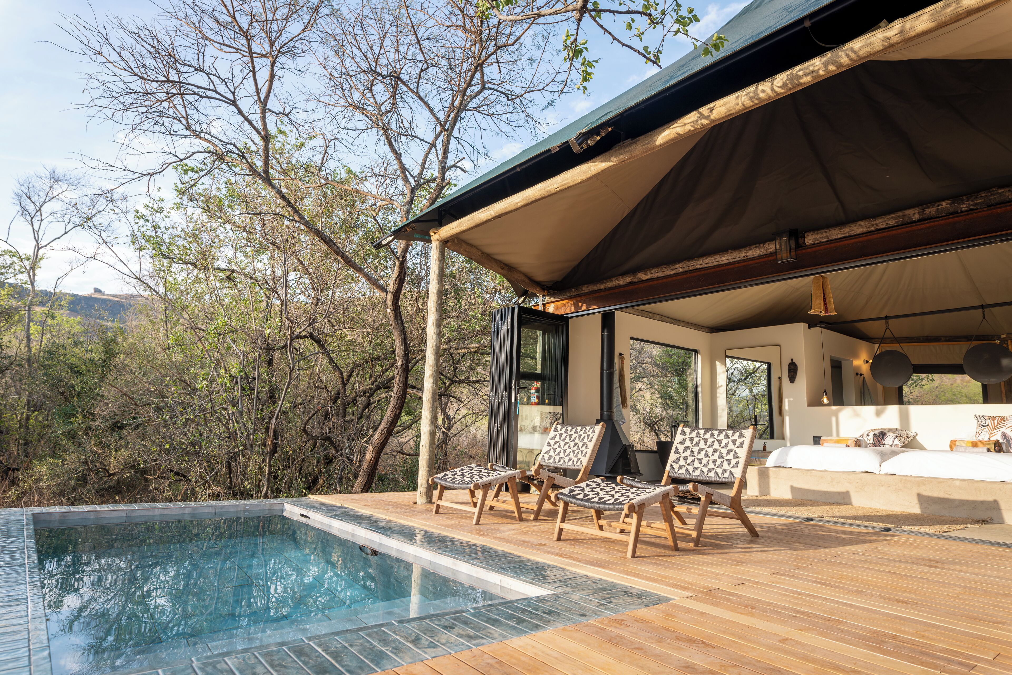 A poolside area with a wooden deck, lounge chairs, and a view of the surrounding trees.