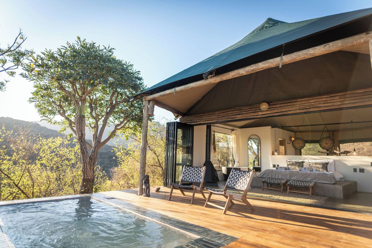 A luxurious outdoor lounge area with a pool, wooden deck, and seating.