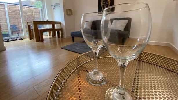 A room with a glass table holding two wine glasses, a sofa, and a chair. - ⭐️Oxford⭐️ modern stylish apartment patio & parking (Oxford)