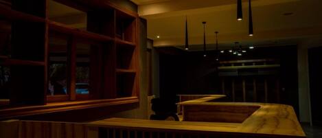 A dimly lit bar area with wooden furniture and pendant lighting.
