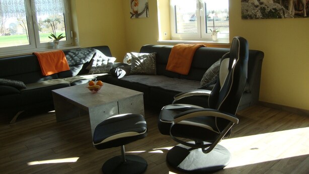 Un salon comprenant un canapé, deux fauteuils, une table basse et un tableau accroché au mur.