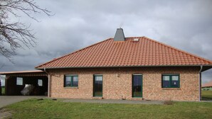 Un bâtiment en briques avec un toit en tuiles, un garage et une pelouse verdoyante.