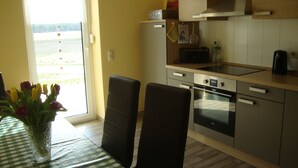 Une petite cuisine avec une table à manger, des chaises et une vue sur un champ par la fenêtre.