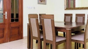 A dining area with a wooden table and six chairs, a wooden door with glass panels, and a framed picture on the wall. - Loumia Residency 3ch (Douala)
