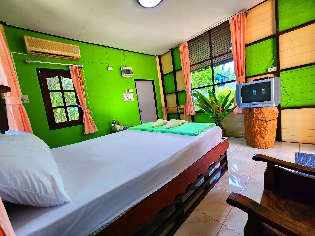 Quarto com uma cama, televisão e janela com cortinas.
