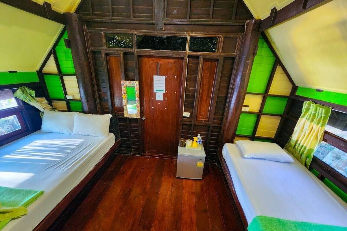 Ein Zimmer mit zwei Betten, einem kleinen Tisch und einer Tür.