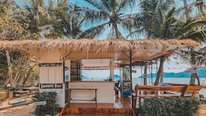 A beachside bar with a thatched roof, wooden benches, and a view of the sea. - Banmae Resort Kohchang (Ko Chang)
