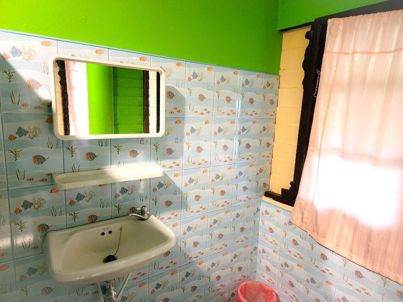 Un baño con lavamanos, espejo y paredes de azulejos.