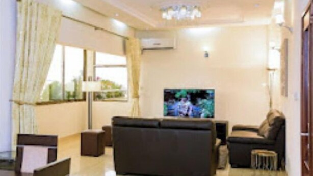 A modern living room with a sofa, a TV, and a dining area with chairs and a table.