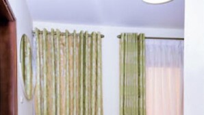 A room with a wooden bench, a small table, and two sets of curtains.