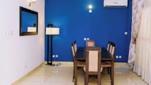 A dining area with a blue accent wall, a chandelier, a table with chairs, and an air conditioning unit.