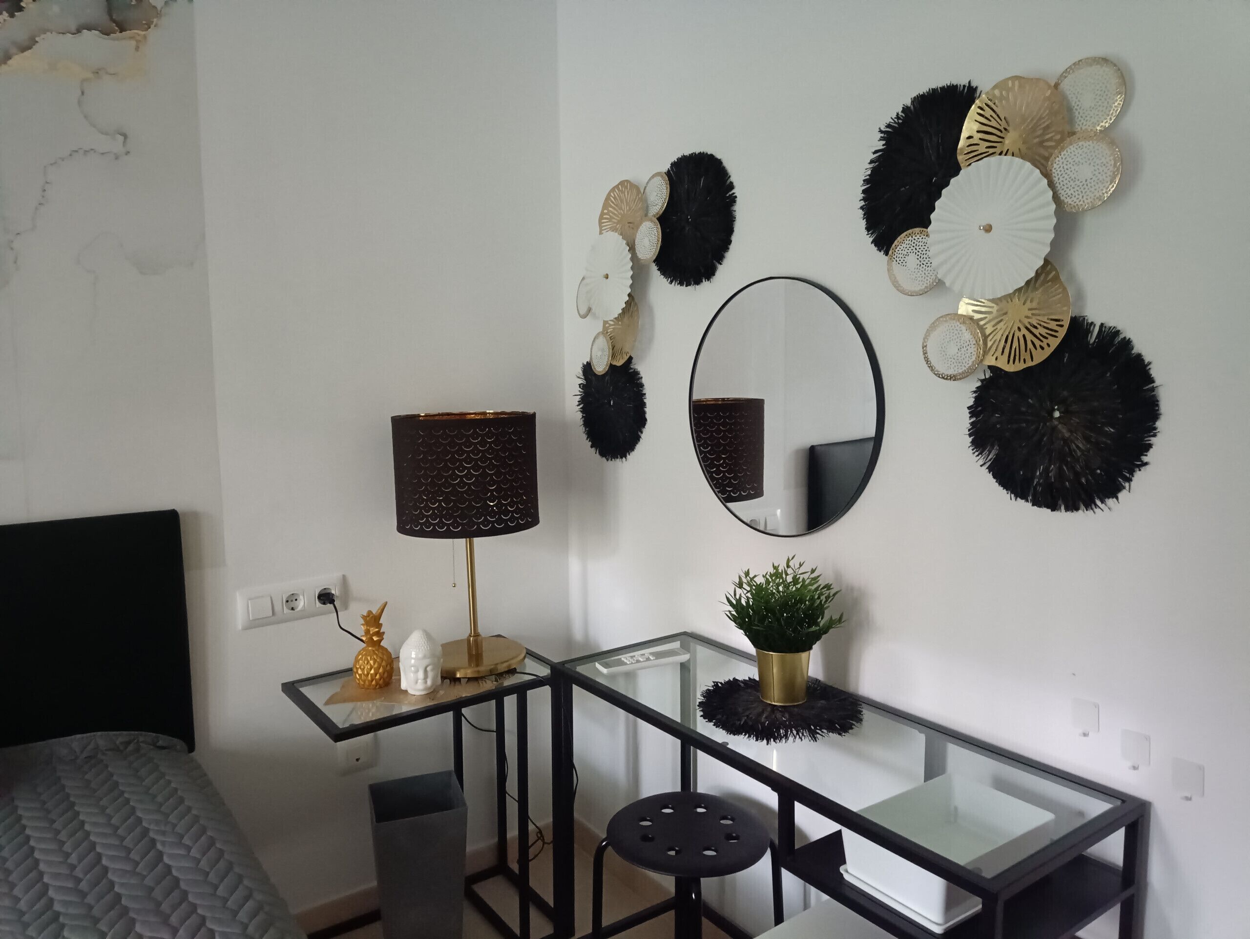 Un dormitorio moderno con cama, escritorio con lámpara, espejo y decoración mural.