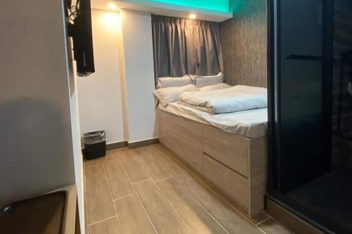 Ein modernes Schlafzimmer mit Bett, einem kleinen Nachttisch, einem Kleiderschrank und einer Schiebetür zu einem Badezimmer.