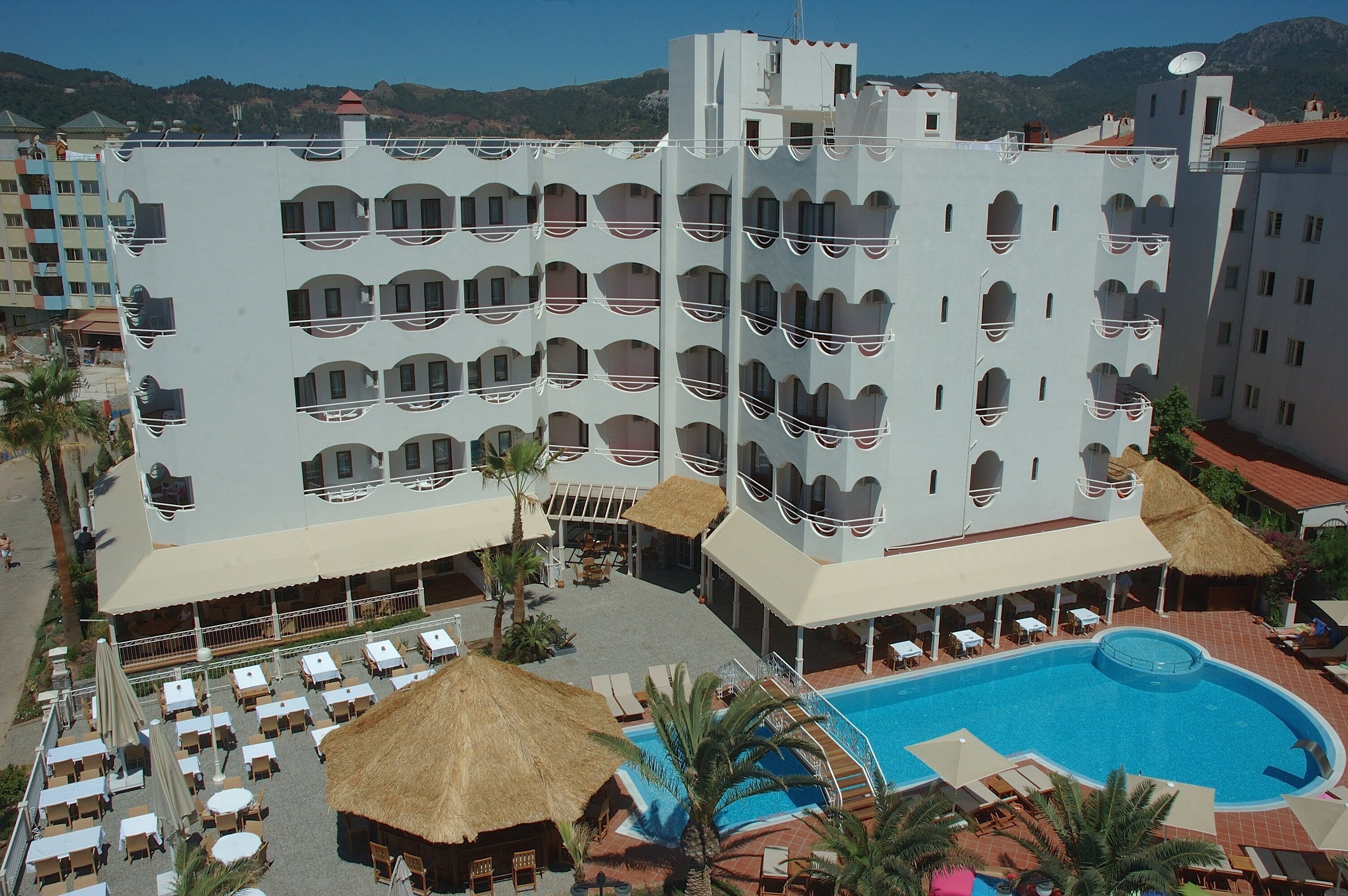 A hotel with multiple balconies, a swimming pool, and outdoor seating areas.