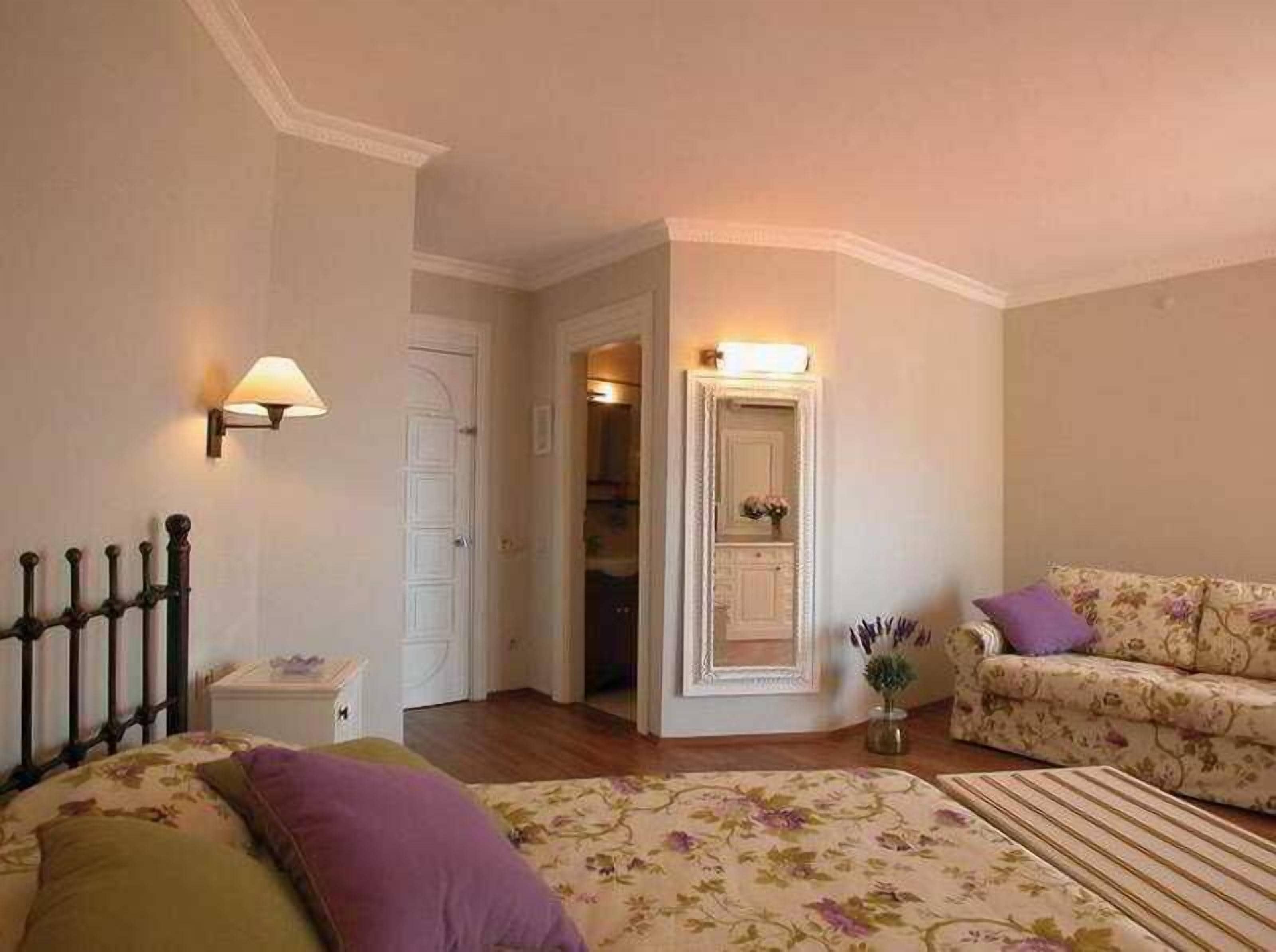 Une chambre à coucher comprenant un lit, une table de chevet, une commode, une chaise et une porte donnant sur une autre pièce.