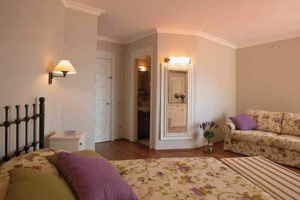 A bedroom with a bed, a nightstand, a dresser, a chair, and a door leading to another room.