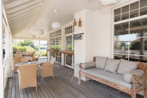 A covered outdoor seating area with wicker furniture, a wooden bench, and hanging light fixtures. - Hawaii Hotel (Marmaris)