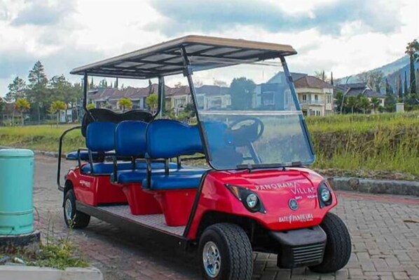 A red golf cart with a roof, blue seats, and a license plate reading "Villas." - TwoSpaces Living at Panorama Villas Batu (Batu)