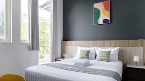 A neatly made bed with pillows, a bedside table with a lamp, and a window with curtains. - Mono Coliving Panorama, Batu (Batu)
