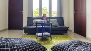 A room with a black sofa, a small table with board games, and a green rug. - Mono Coliving Panorama, Batu (Batu)