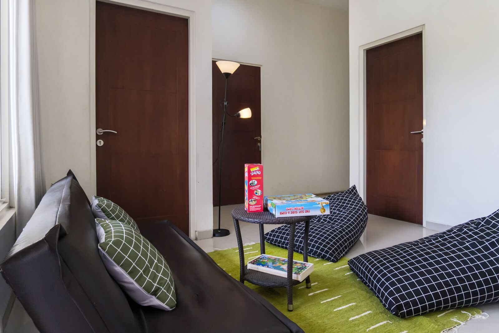 Una habitación acogedora con un sofá, una pequeña mesa con un juego de mesa y dos puertas.