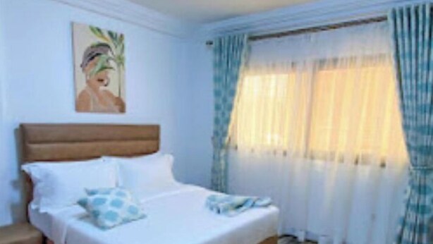 Ein Schlafzimmer mit einem hölzernen Bett, weißer Bettwäsche, einem Nachttisch und einem Bild an der Wand.