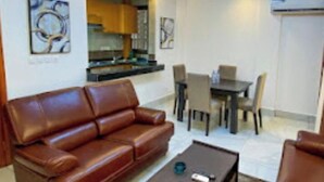 Ein Wohnzimmer mit braunem Ledersofa, einem Couchtisch und einem Essbereich mit Tisch und Stühlen.