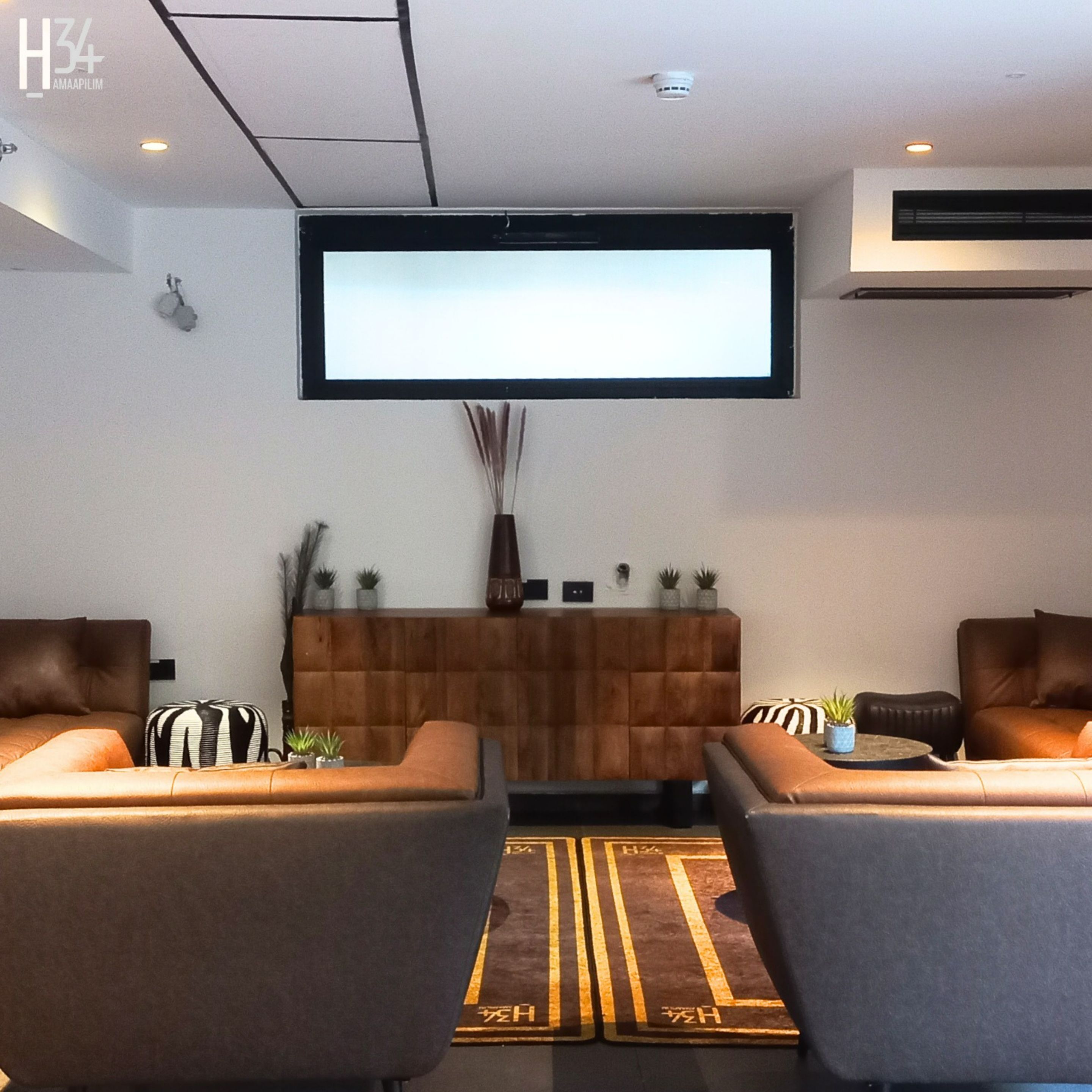Una sala de estar moderna con un televisor de pantalla plana grande montado en la pared, dos sofás, una pequeña mesa de centro y un jarrón decorativo.