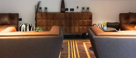 Una sala de estar moderna con un televisor de pantalla plana grande montado en la pared, dos sofás, una pequeña mesa de centro y un jarrón decorativo.