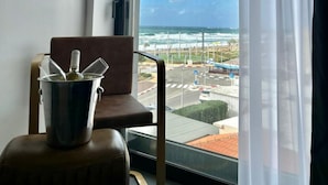 Una habitación con vista al océano y una silla con una botella de vino sobre una mesa.