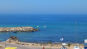 Vista costera con un rompeolas rocoso, mar tranquilo y cielo despejado.