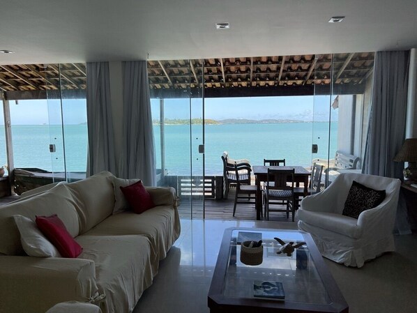 A spacious living area with a large glass door leading to a balcony overlooking a body of water.