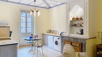 A modern kitchen with a washing machine, a dining area with a table and chairs, and a cozy seating area with a sofa.
