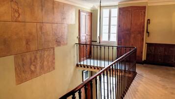 Una escalera con barandilla de madera y balaustres negros, que lleva a una plataforma con vistas a una puerta y una ventana.