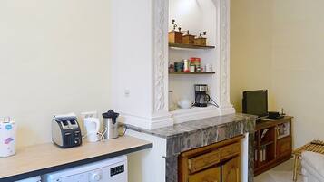 A compact kitchen with a washing machine, a coffee maker, and a microwave.