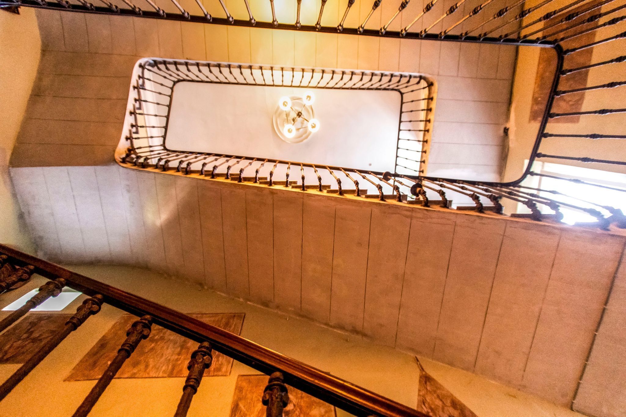 A staircase with a metal railing and a wall-mounted light fixture.