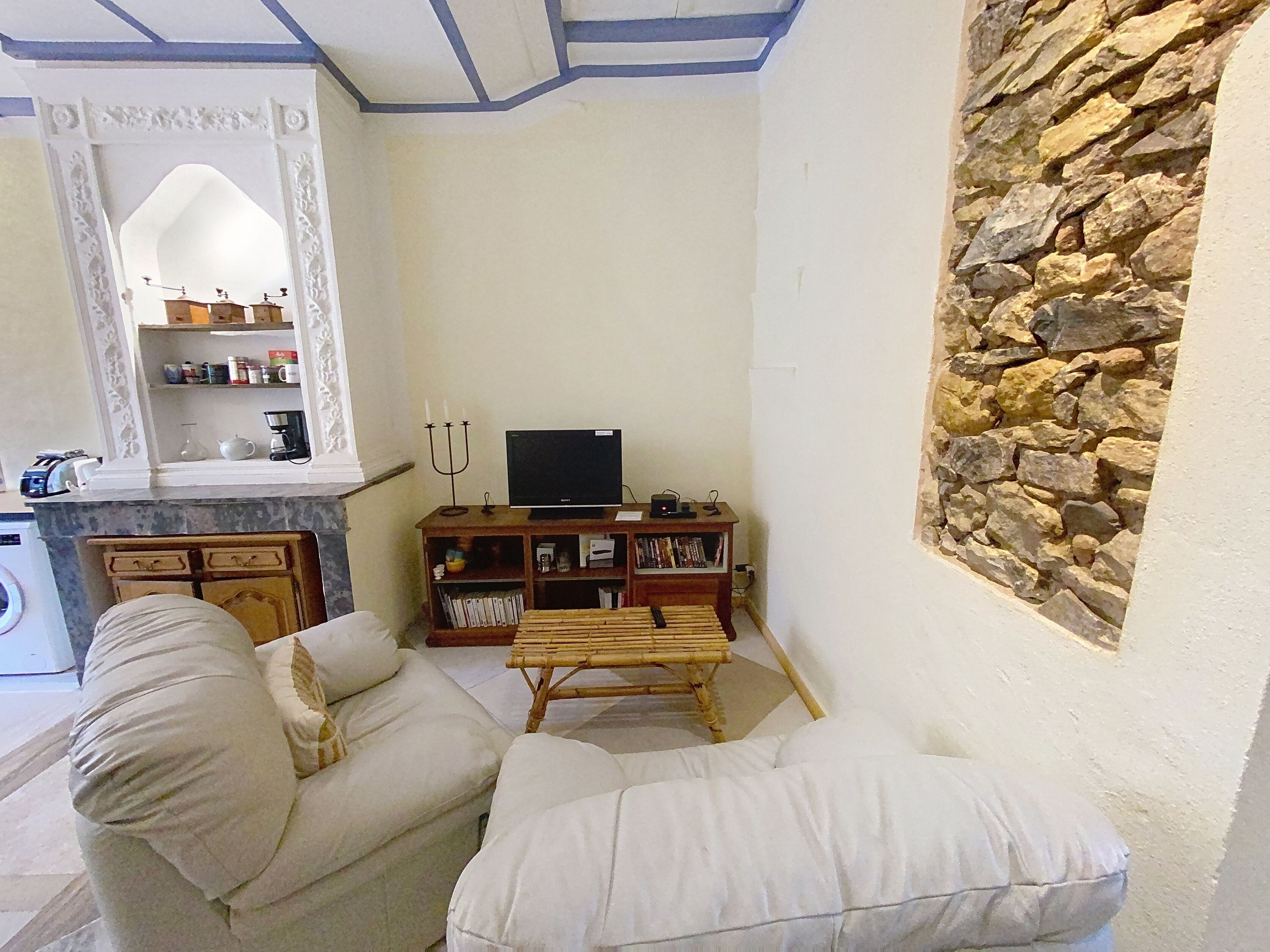 Una sala de estar con una pared de piedra, un televisor sobre un mueble de madera y un sofá.
