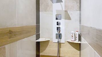 Une douche moderne dotée d’un pommeau de douche à main et d’un panneau de commande fixé au mur.