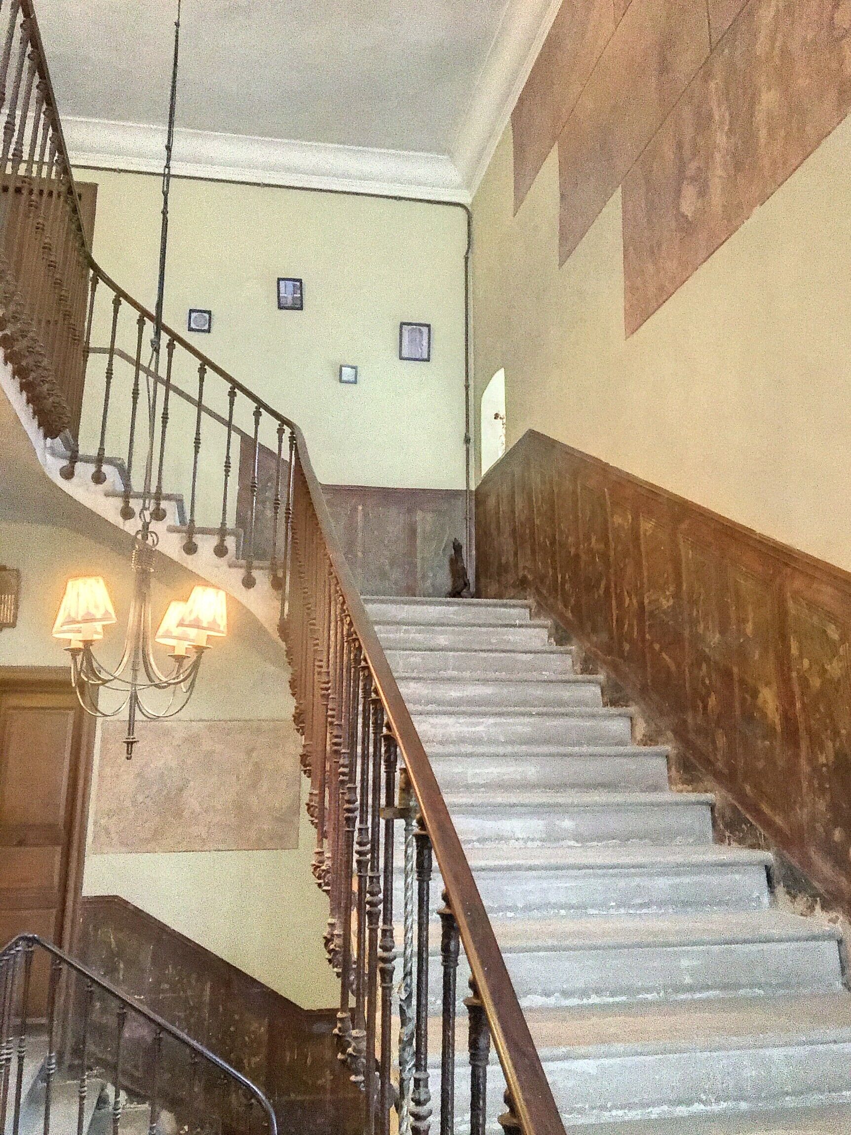 A grand staircase with ornate railings and a chandelier.