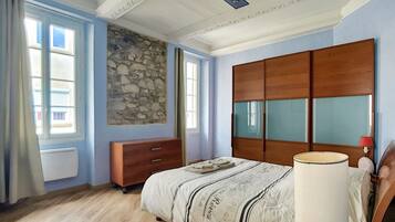 Un dormitorio con una cama grande, un armario de madera, una pared de piedra y una ventana con cortinas.