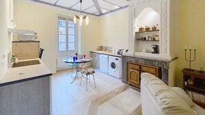 A modern kitchen with a dining area, a washing machine, and a built-in oven. - Résidence Verdi (Bedarieux)