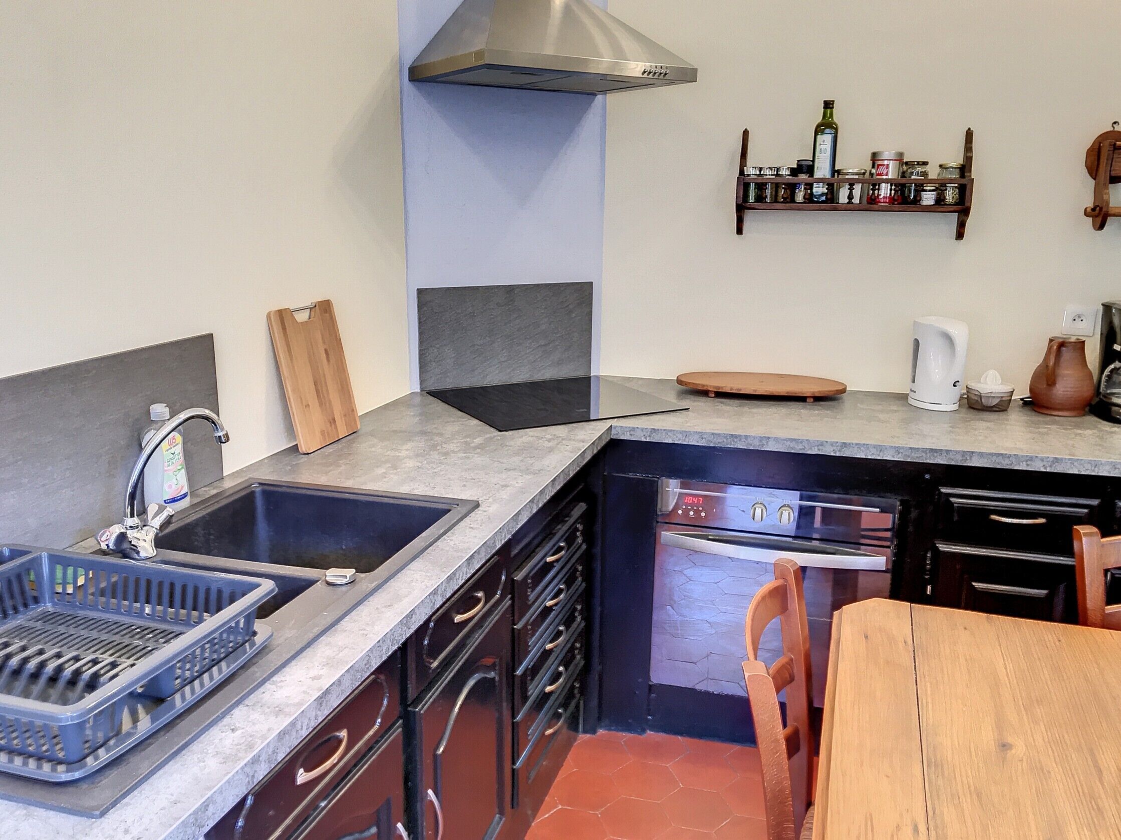 A compact kitchen with a sink, dishwasher, and a wooden table.