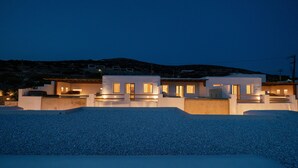 A modern house with multiple levels, large windows, and a well-lit exterior. - Utopia Suites by Anna Platanou - Adults only (Paros)