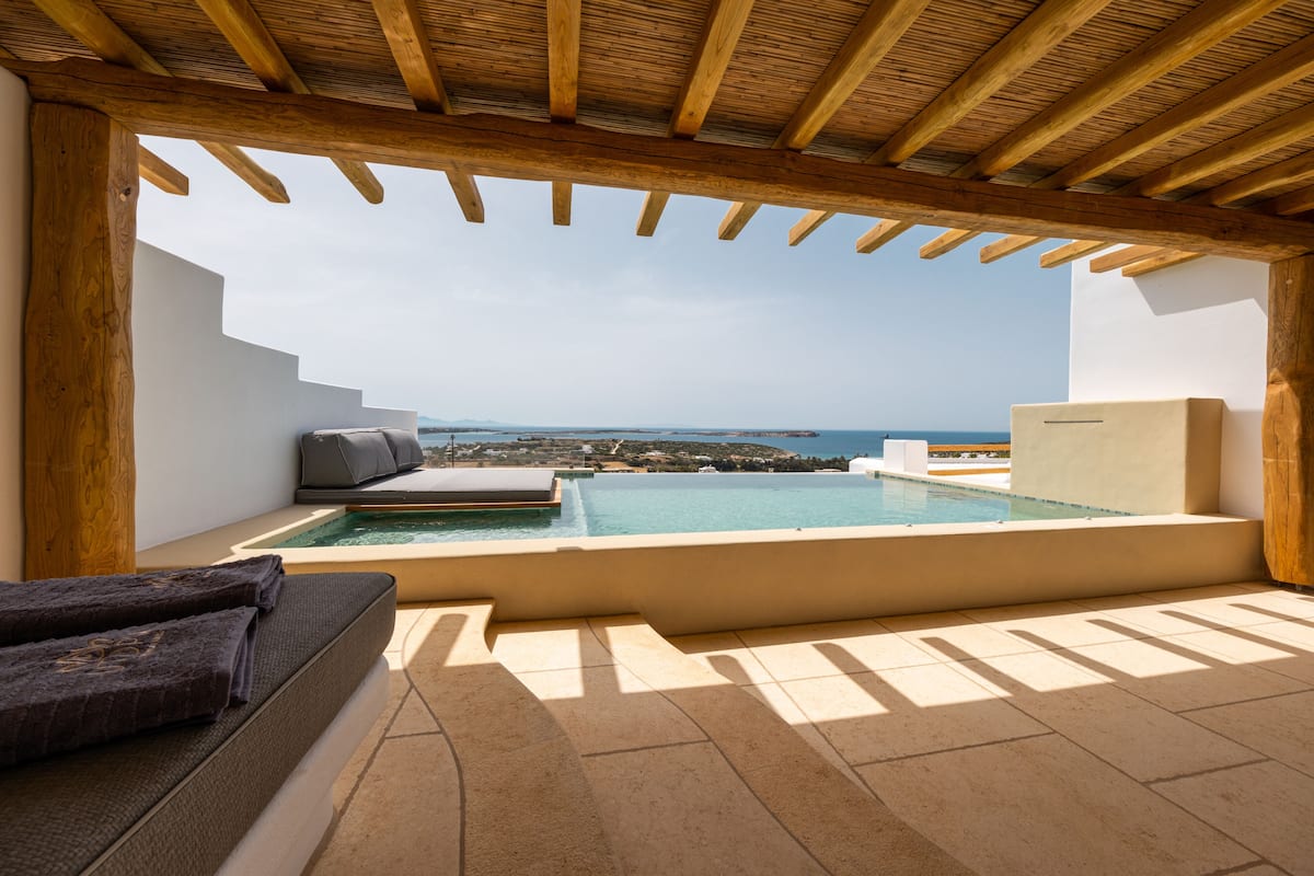 A rooftop terrace with a pool, seating area, and a view of the sea.