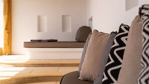 A modern interior with a sofa, cushions, and a bench against a white wall. - Utopia Suites by Anna Platanou - Adults only (Paros)