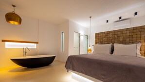 A modern bedroom with a large bed, a built-in sink, and a unique brick-patterned headboard. - Utopia Suites by Anna Platanou - Adults only (Paros)