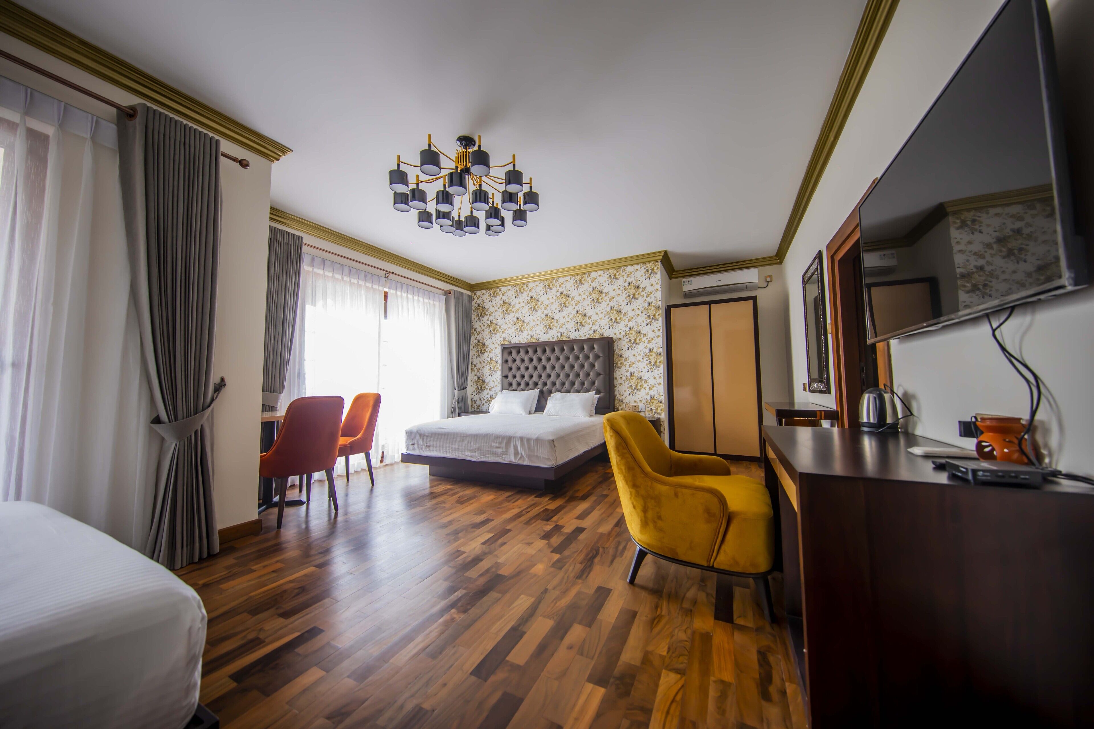 Una habitación de hotel con cama, escritorio, silla, armario y espejo.