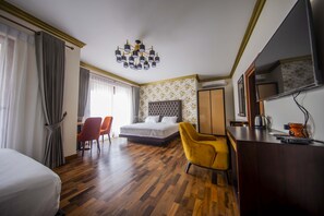 Quarto de hotel com cama, escrivaninha, cadeira, guarda-roupa e espelho.